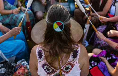 native american woman with back to camera leads drum circle
