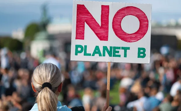 Woman seen from the back holding a No Planet B placard