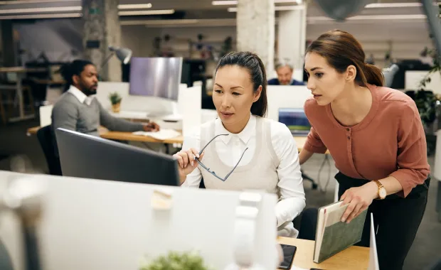 Two businesswomen working collaboratively on a desktop in an office