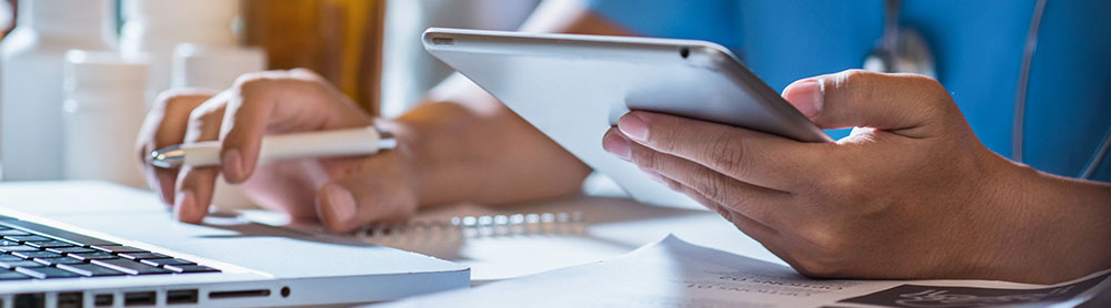 Doctor using technology Close up of Doctor using a laptop and tablet device