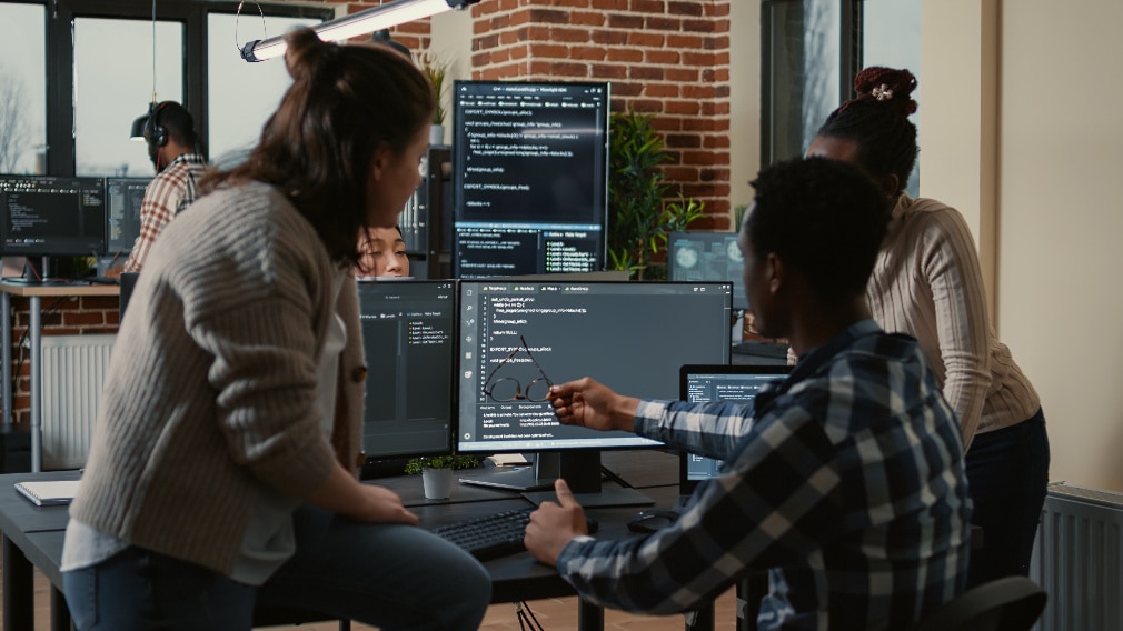 Team of professionals looking at code testing on a computer screen 