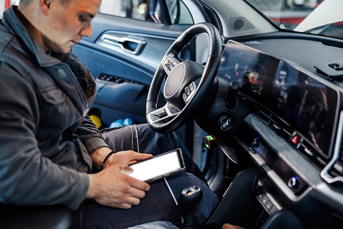 a police officer in a vehicle looking at a tablet 