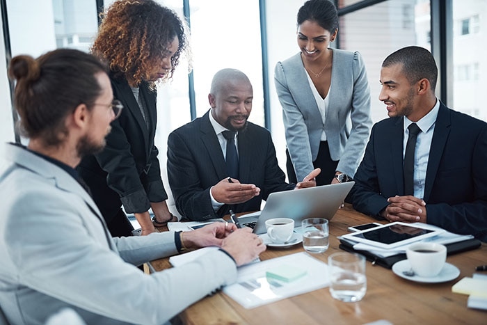 Discussion, planning and business people with laptop in office for financial review, strategy and collaboration. Meeting, teamwork and men and women working on report, group project and proposal