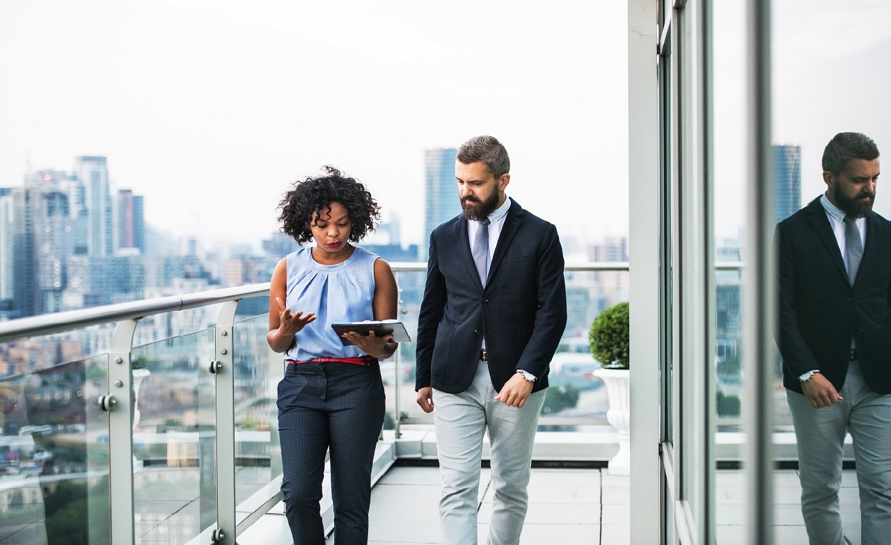 Two colleagues walk outside office discussing cyber risk Two colleagues walk outside office discussing cyber risk