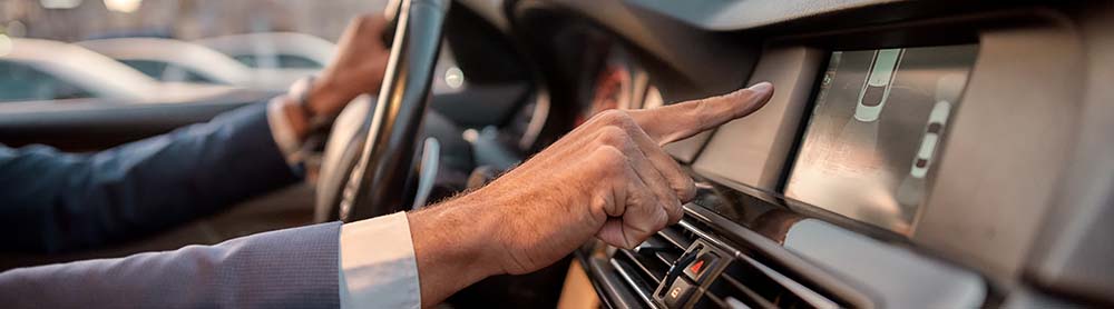 Person's hand reaching for screen on the car dashboard