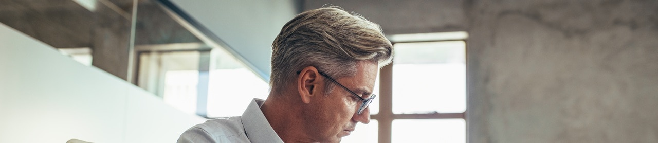 businessman-working-computer-281095415 Business man looking down at a computer