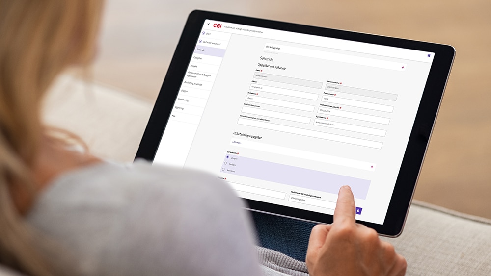 En person håller en surfplatta som visar ett digitalt formulär från CGI. Formuläret har sektioner för att fylla i uppgifter om sökande, inklusive namn, kontaktuppgifter och utbildningsinformation.