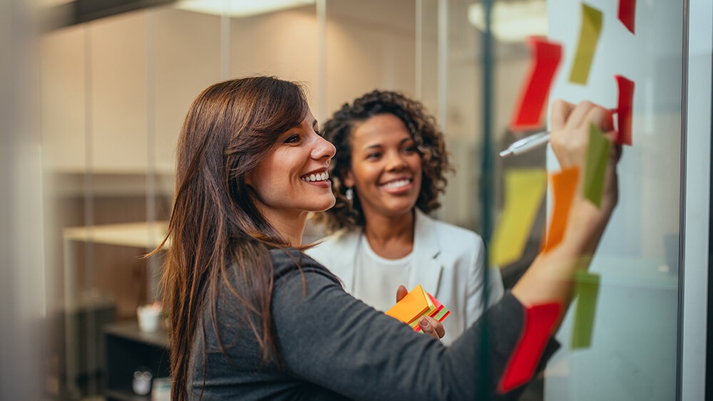 two employees looking at kanban board