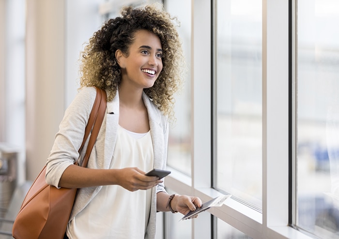 A woman at an airport holding her boarding pass and passport 