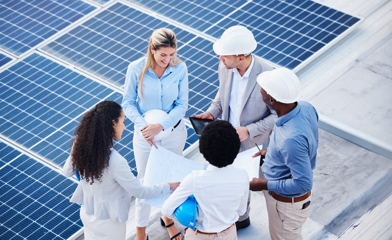 Group of people standing around solar panels having a discussion