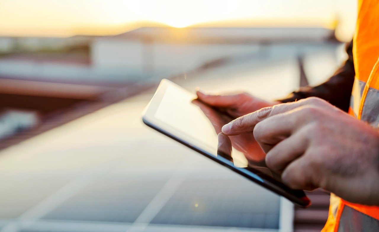hand-using-tablet-control-solar-panels-490843042 Hand using a tablet overlooking solar panels