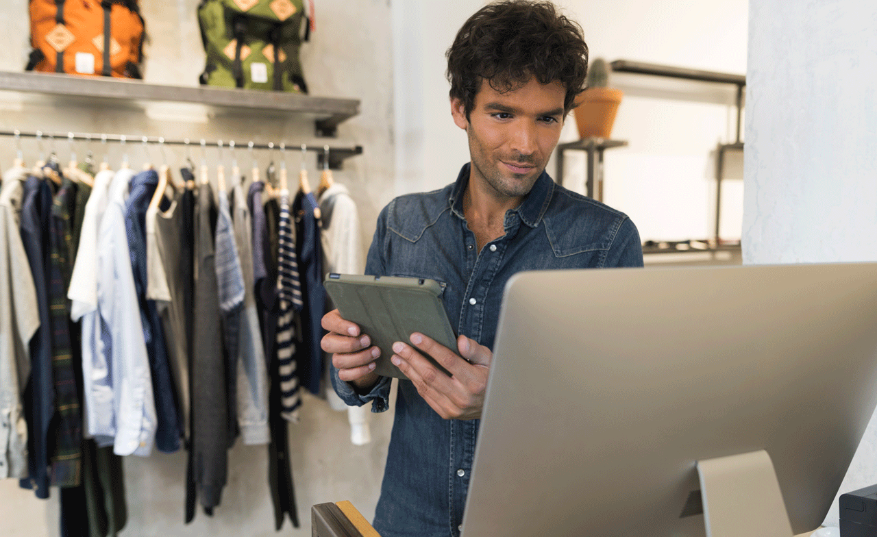 Einzelhändler vergleicht seinen Warenbestand am Tablet und am Bildschirm