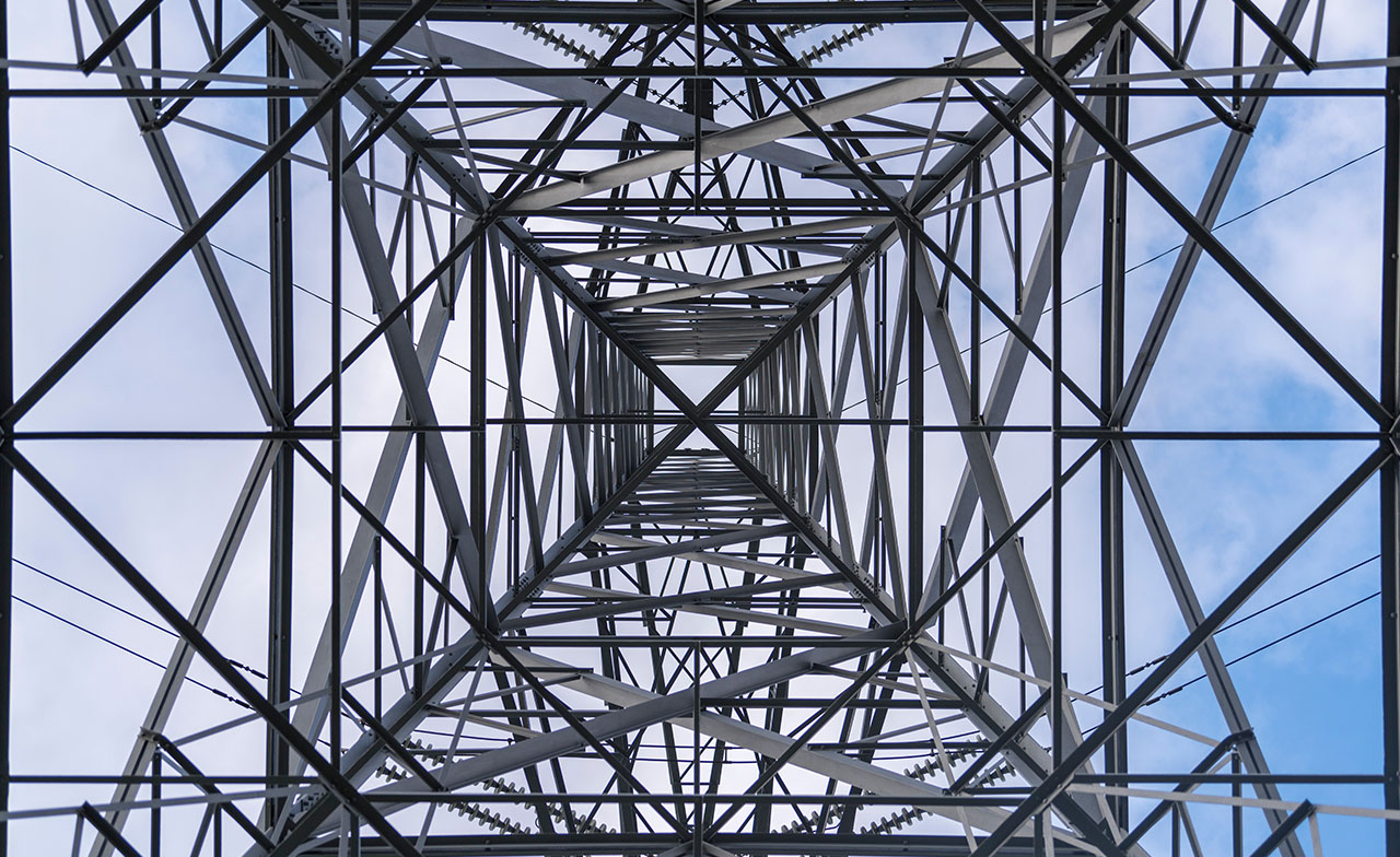 IS Suite Vi utvikler 2 Blikk opp gjennom stålkonstruksjon på en høyspentmast mot himmelen