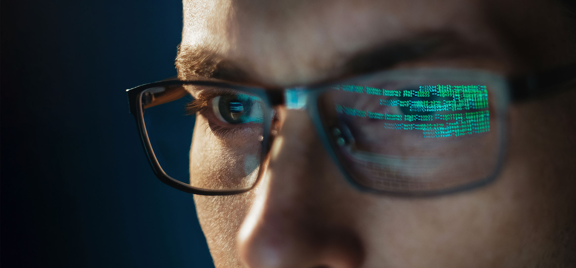 Mann med kode reflektert i brillene – illustrerer bruk av kunstig intelligens i systemutvikling Mann med kode reflektert i brillene – illustrerer bruk av kunstig intelligens i systemutvikling