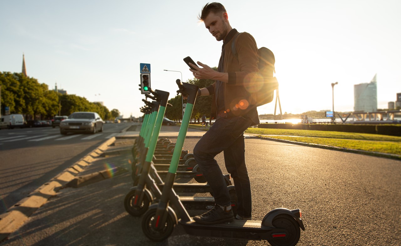 Un homme déverrouille un scooter électrique à l'aide d'un téléphone portable