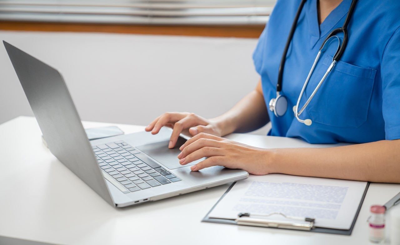 Medical professional entering data on a laptop