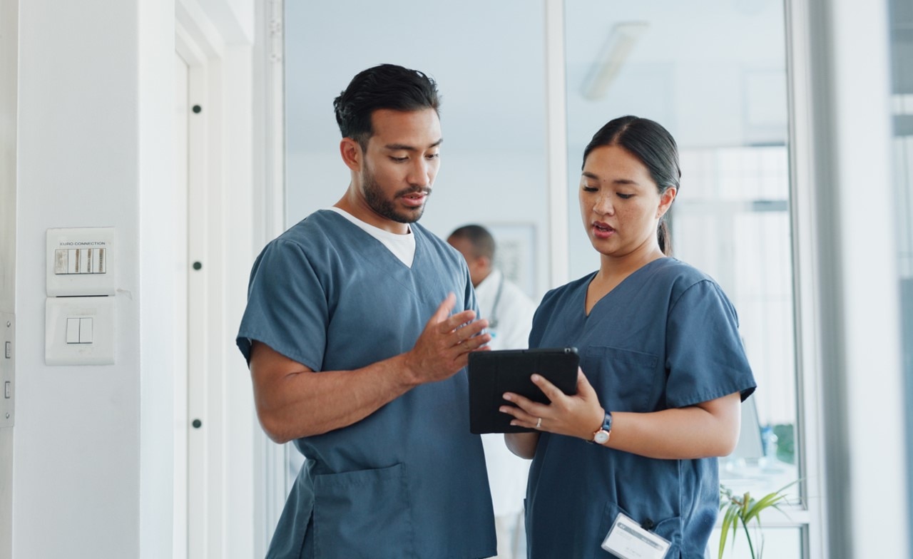 Medical professionals discussing report on a tablet