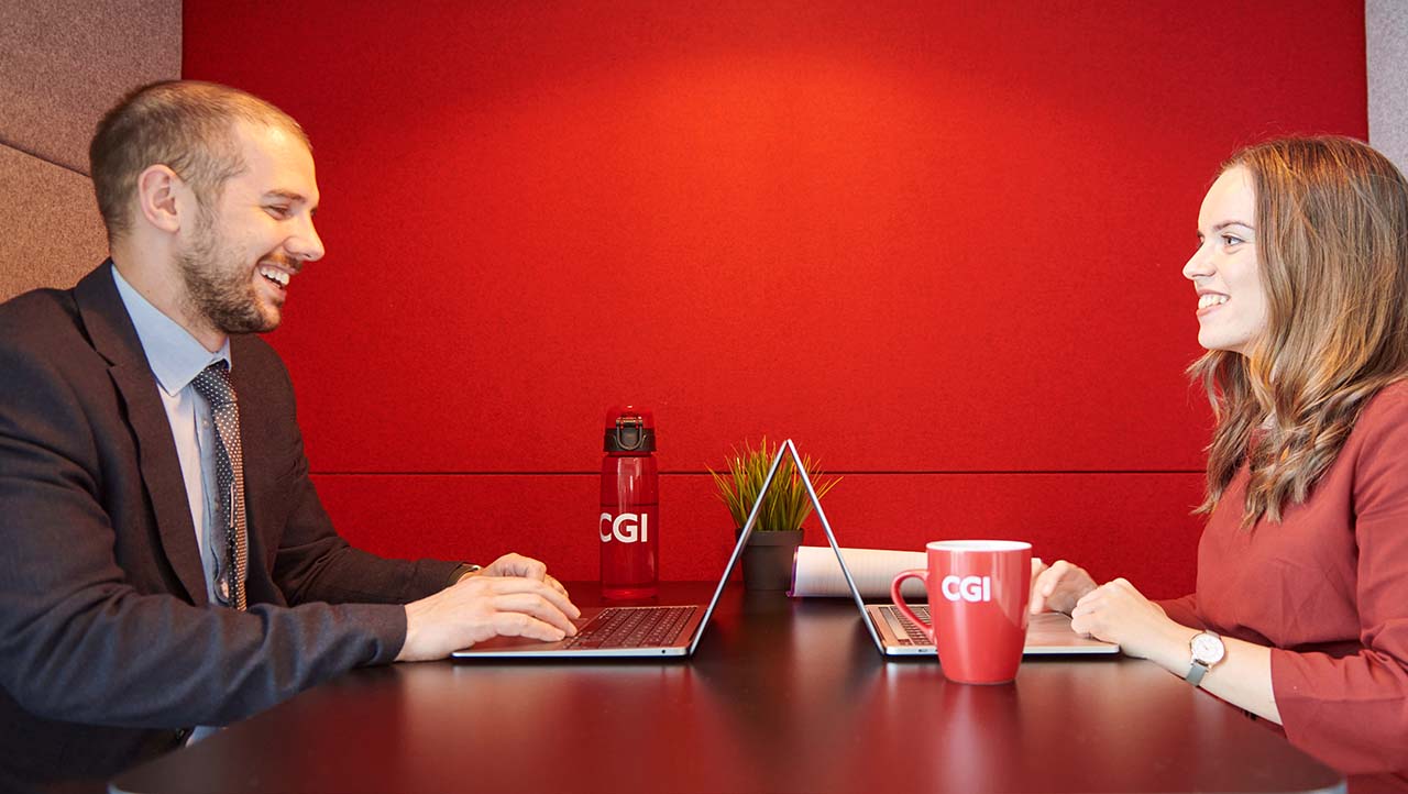 Male and female CGI Partners laughing in a meeting 