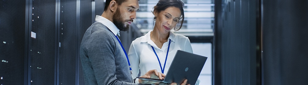 Engineers in a databank room discussing business over a laptop