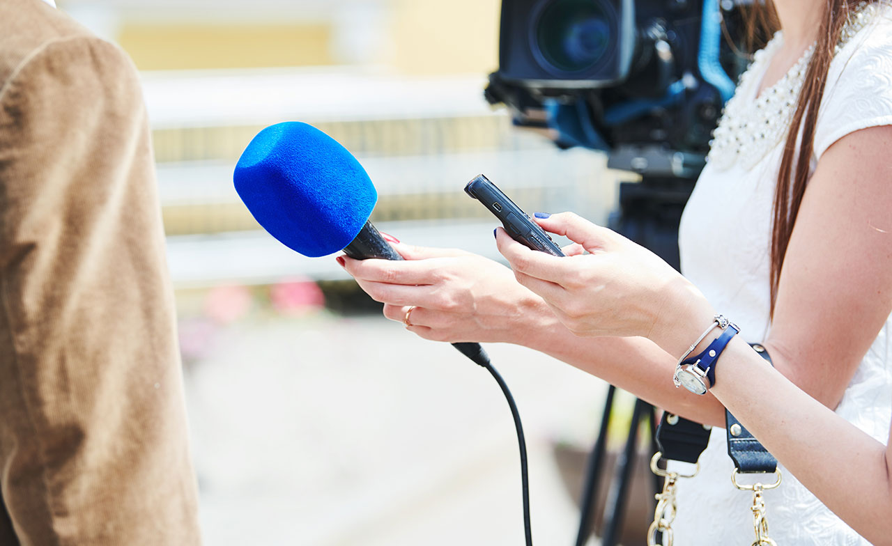 Person being interviewed by an interviewer holding a blue microphone