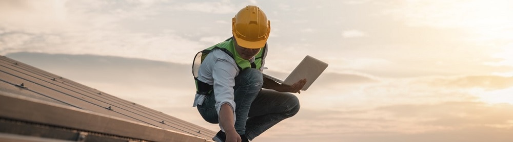 A person wearing a hard hat inspecting solar panels