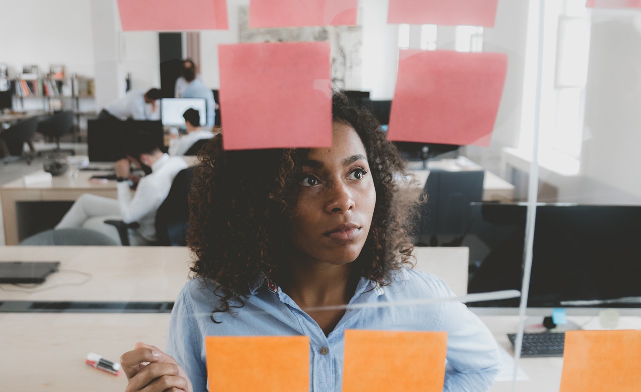 A person looking at a glass wall with sticky notes