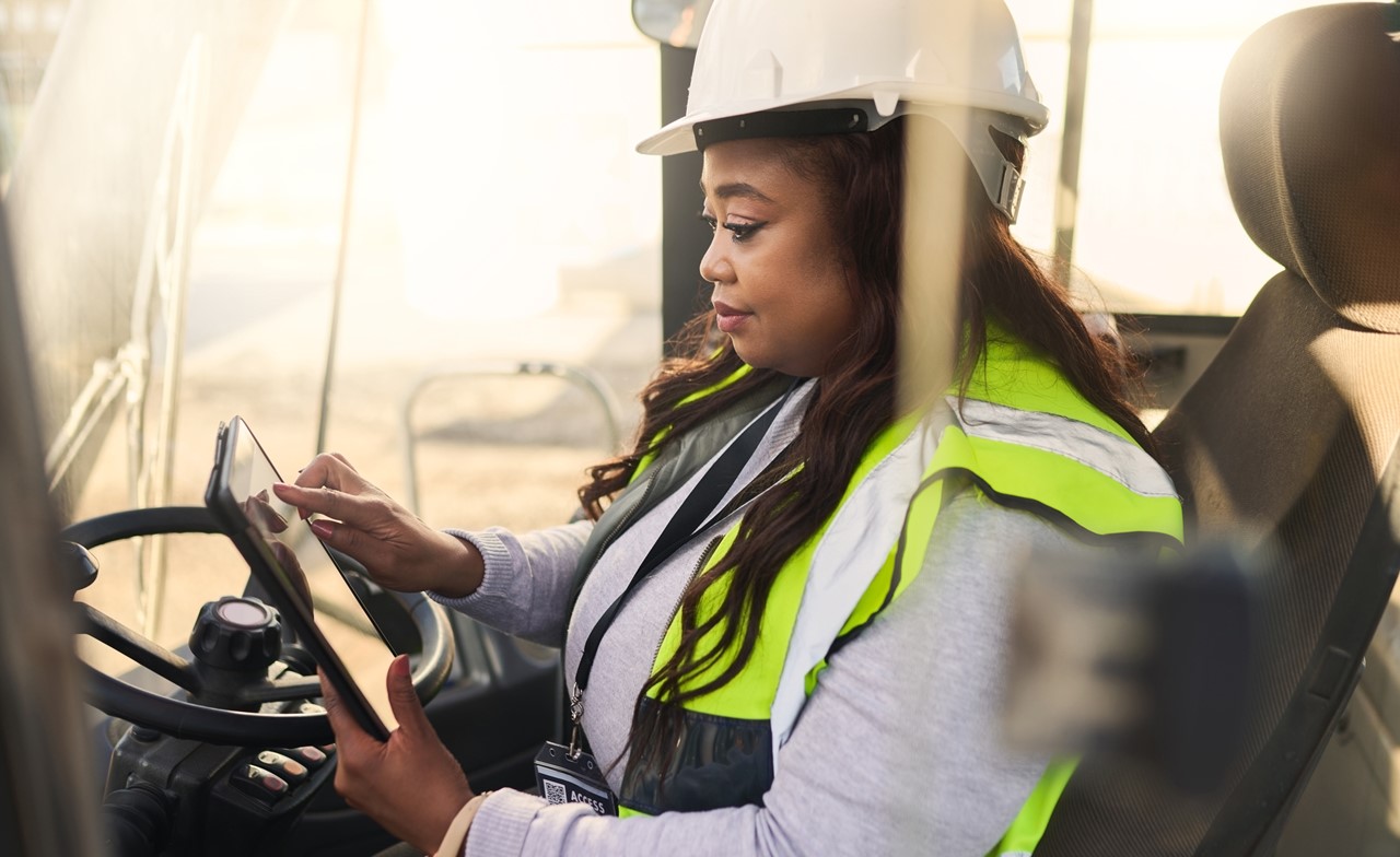 A person wearing a safety vest and hard hat using a table in the field