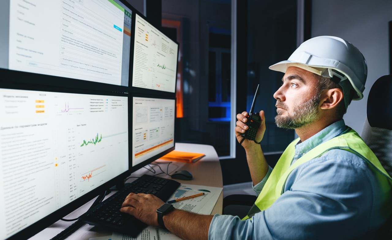 A person wearing a hard hat using a walkie talkie