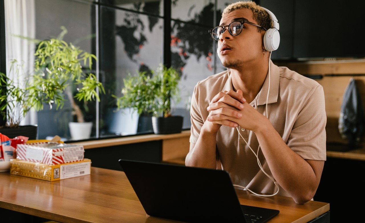 A person wearing headphones sitting at a desk with a computer