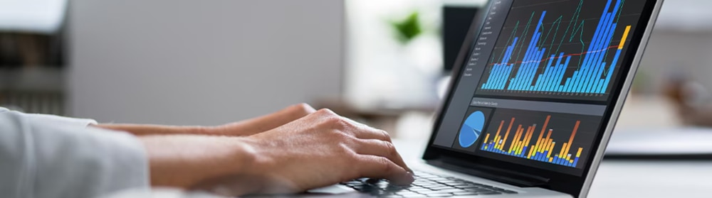 Person's hands resting on lap[top showing data charts