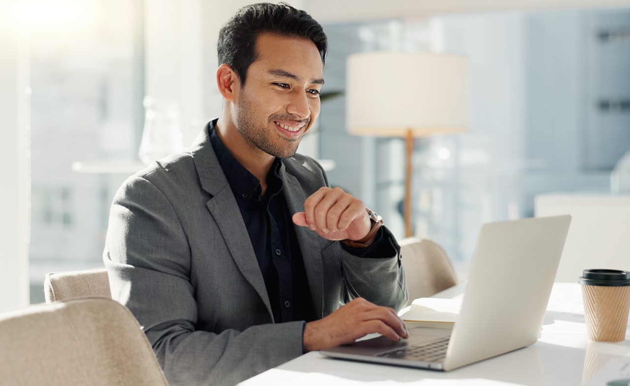 A smiling man in an office using a laptop