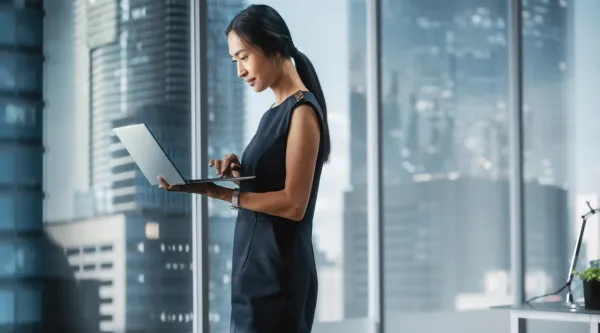 executive viewing a laptop in a boardroom in front of a window