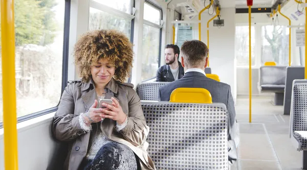 Eine Frau sitzt in einem Bus und schaut auf ihr Handy
