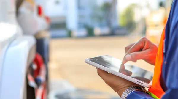 Person with tablet device standing next to vehicle