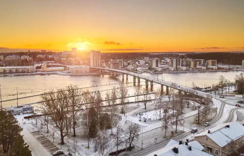 Aerial view of Joensuu, Finland covered in snow with the sun rising in the horizon. 