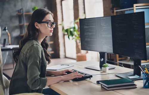 A professional business woman sitting at a computer looking at code 