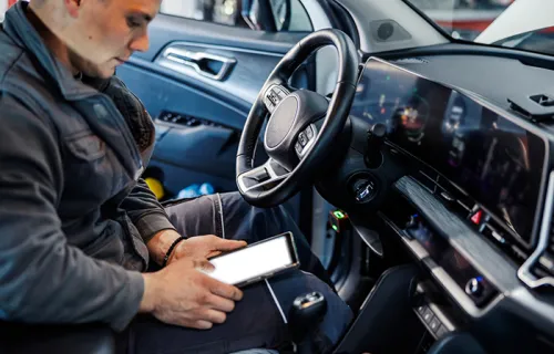 a police officer sitting in a vehicle looking at a tablet 