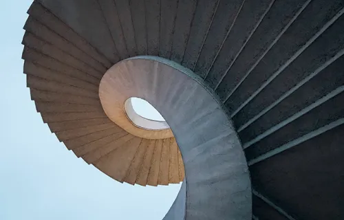 Low angle shot of curved spiral stairs under a bright blue sky