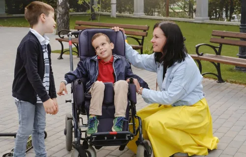  A woman and a boy, along with a child in a wheelchair, are engaged in a joyful conversation