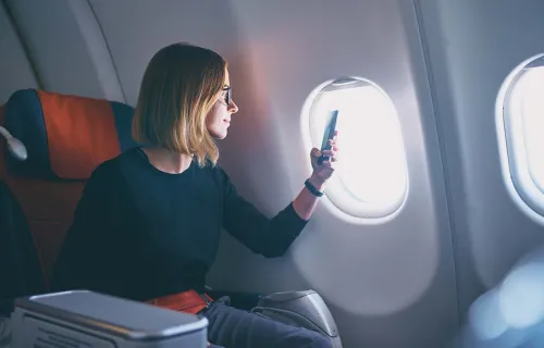 mujer tomando una foto desde la ventanilla de un avión