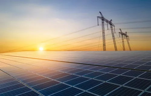 Solarmodule und Stromleitungen bei Sonnenaufgang als Symbol für die Transformation der Utilities-Branche