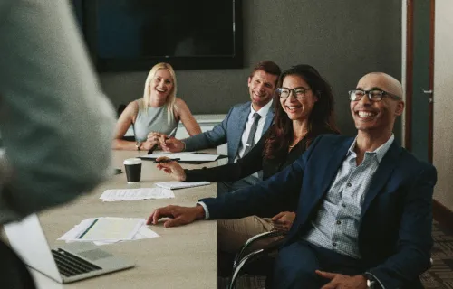 3 team members in a meeting smiling at the speaker 