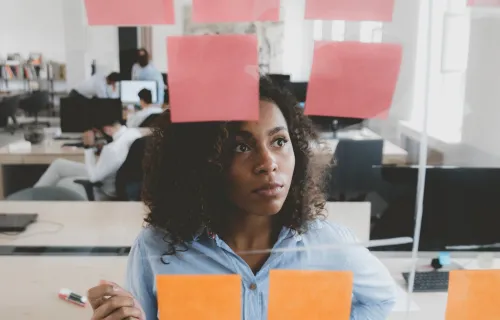 consultant looking at a glass wall with sticky notes