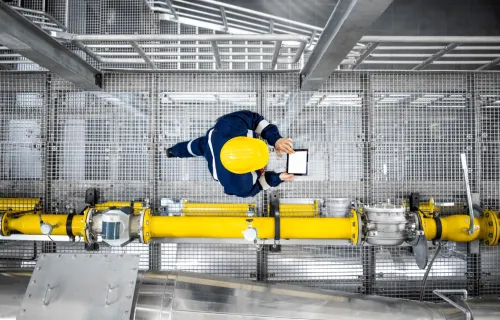 aerial view of an engineer evaluating data on a tablet while walking through a plant