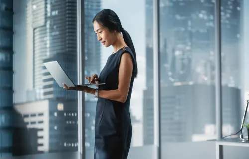 executive viewing a laptop in a boardroom in front of a window