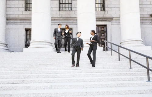 Group of people standing on stairs outside of a government building