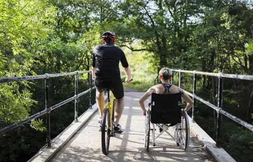 Cyklist och rullstolsbunden som tränar tillsammans