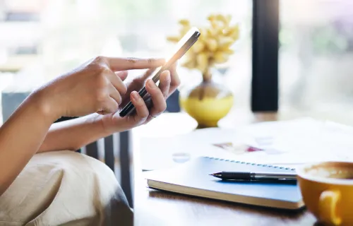 Person sitting at table, holding mobile phone