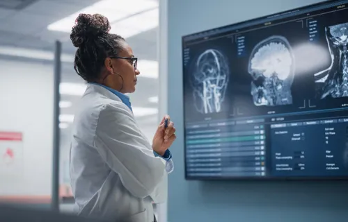 Ärztin schaut sich Röntgenaufnahmen an einem großen Bildschirm an