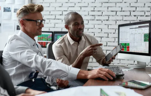 Two male professionals sitting down in front of a computer screen 